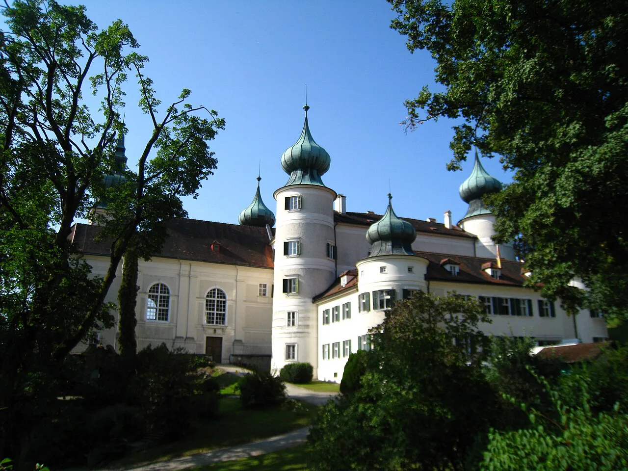 The onion-domed towers of Artstetten Castle among the trees.