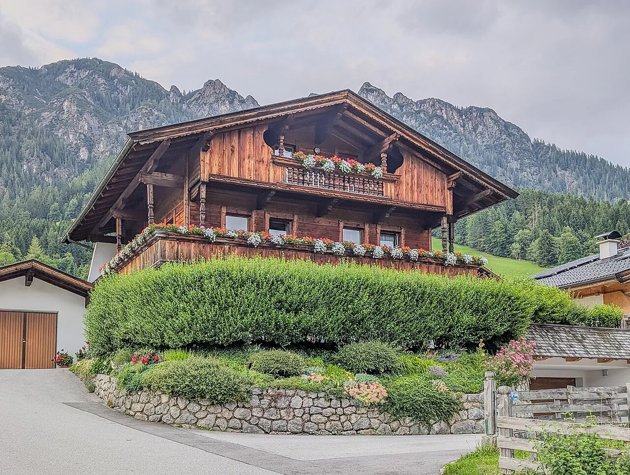 A traditional timber chalet with flower-lined balconies in Alpbach, Tyrol.