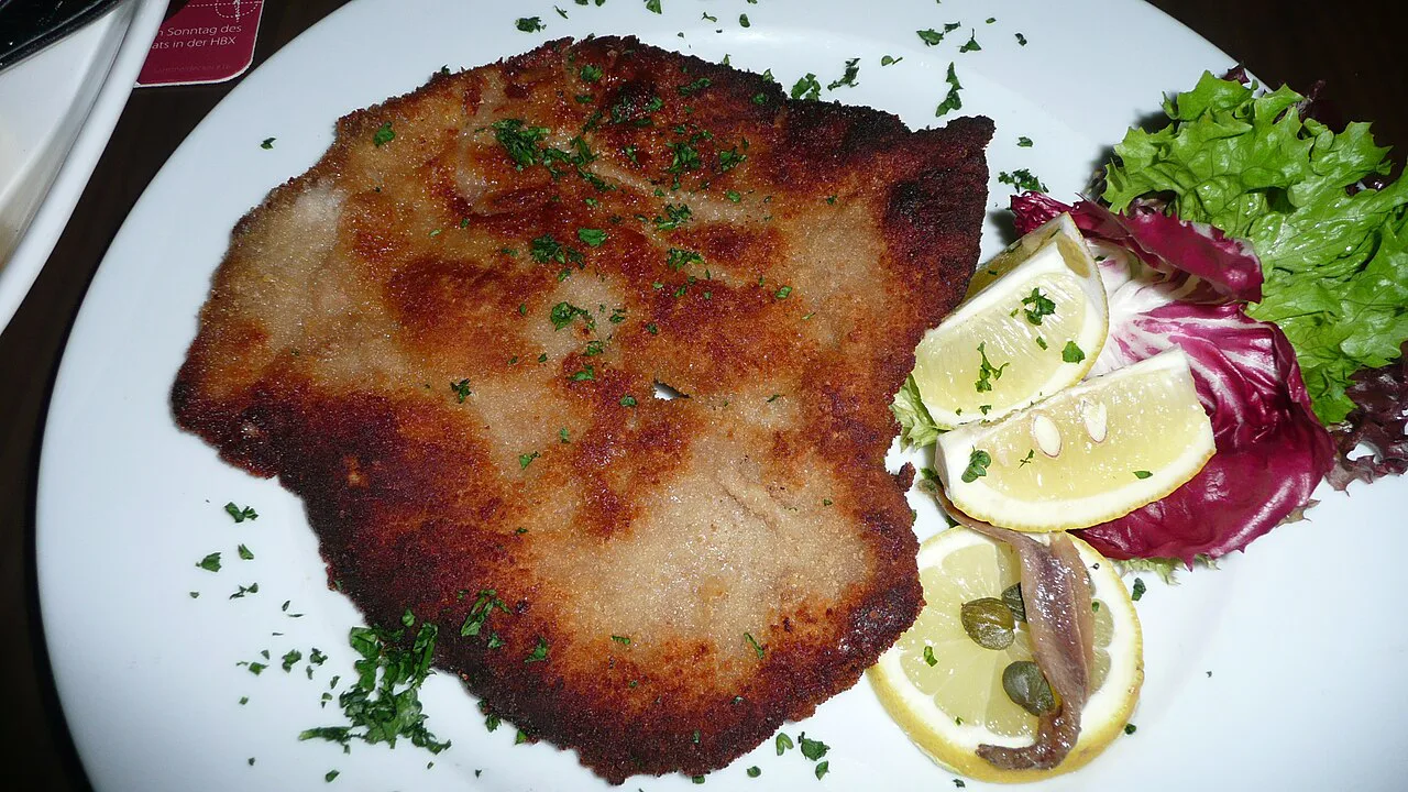 A breaded Wiener Schnitzel served with lemon, capers, anchovy and a side salad.