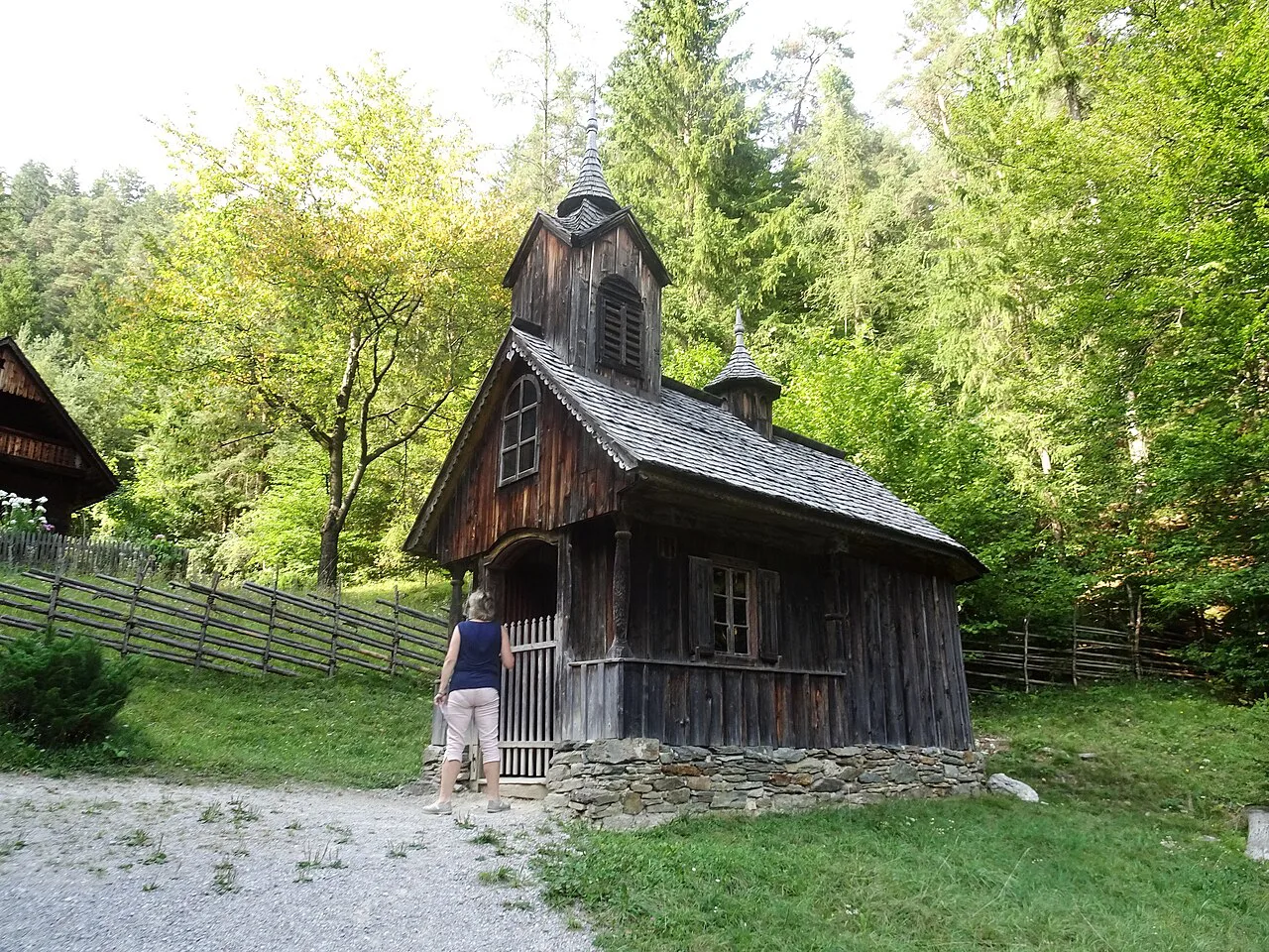 A small wooden chapel among trees at the Austrian Open-Air Museum Stübing.