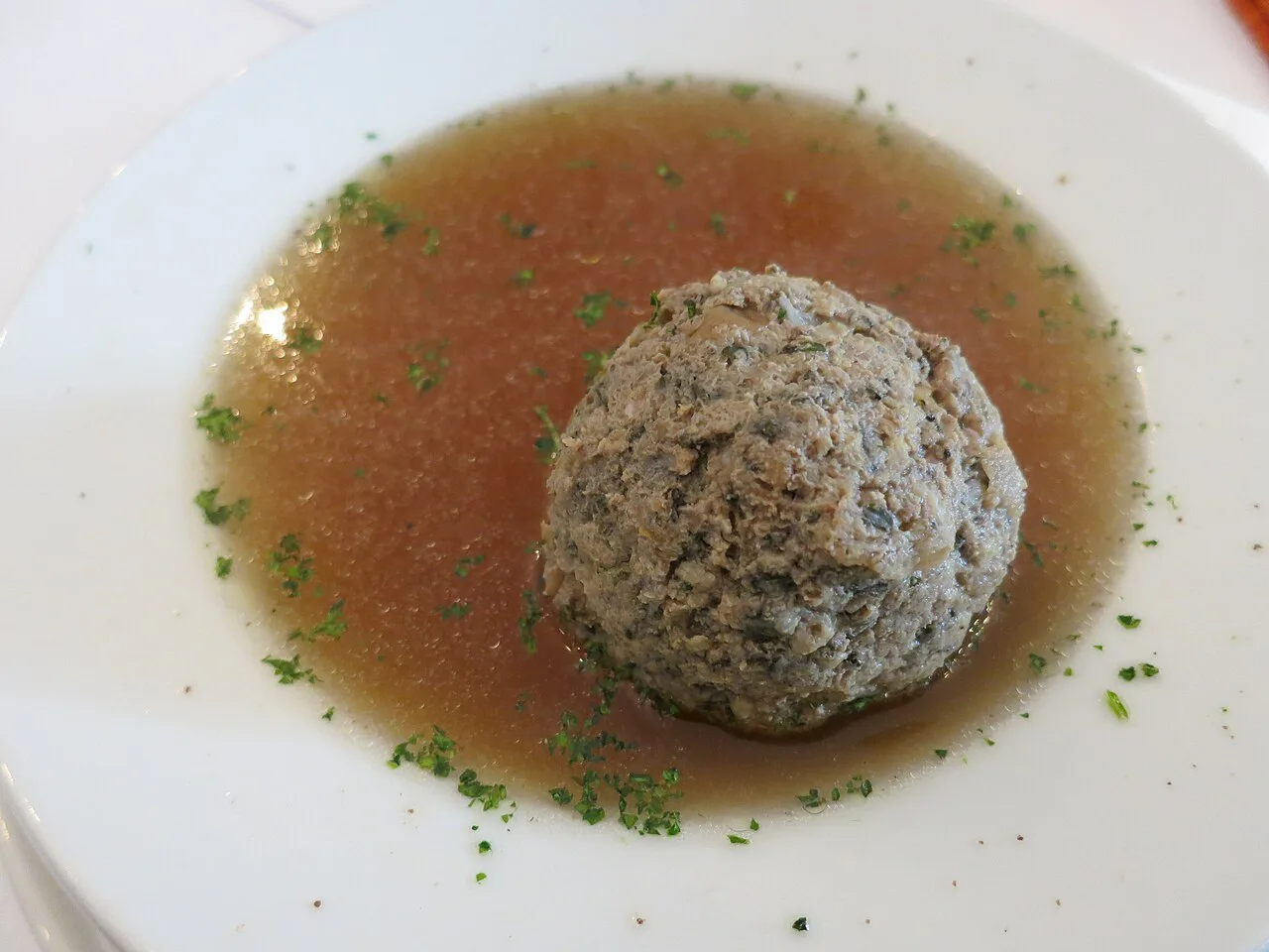 Leberknödelsuppe, a liver dumpling served in clear broth with chives.