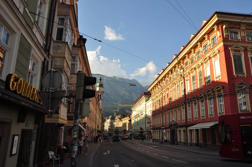 A street of historic buildings in central Innsbruck with mountains in the distance.