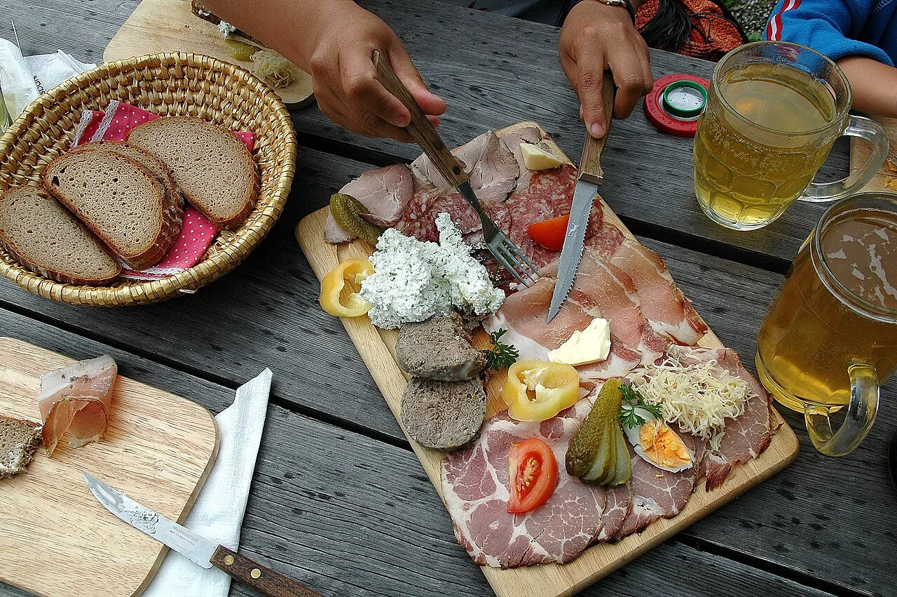 A Brettljause with bread and cold meats, served with glasses of cider.