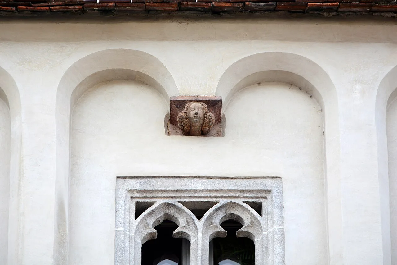 A carved head above a Gothic tracery window on the Bummerlhaus facade in Steyr.