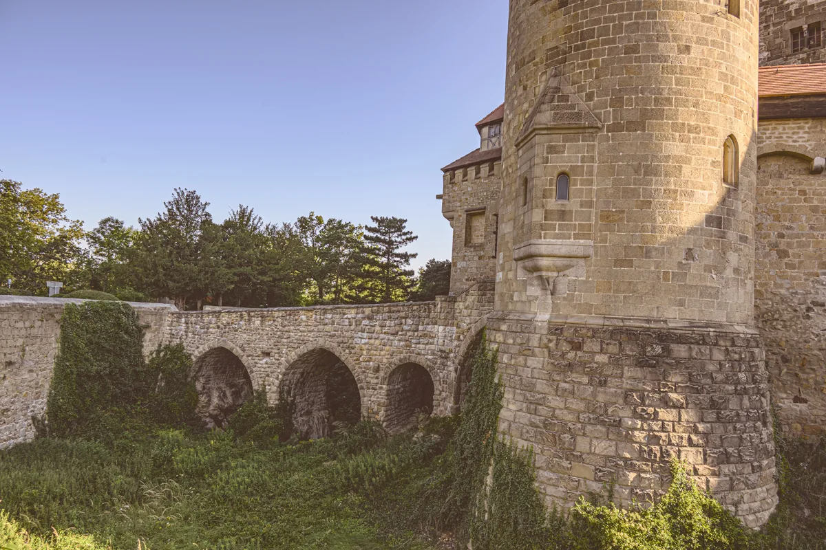 A tower and arched bridge of Burg Kreuzenstein in early morning light.