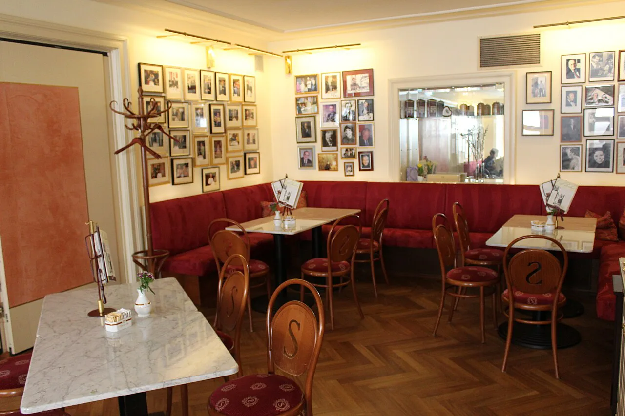 Red banquettes and marble tables inside Café Sacher in Innsbruck.