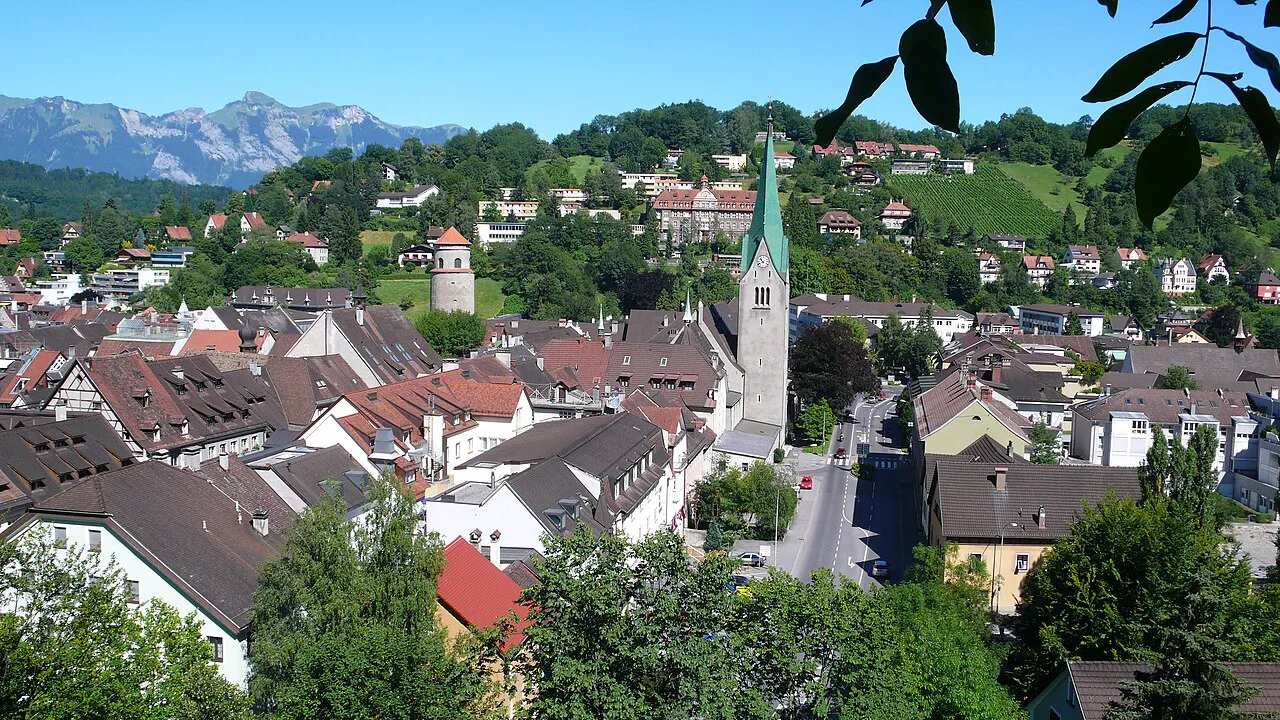 Feldkirch's old-town roofs and church tower with mountains behind.