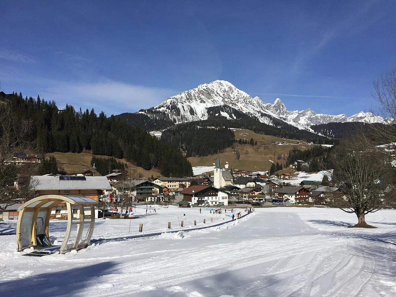 Snowy village slopes at Filzmoos with mountains behind.