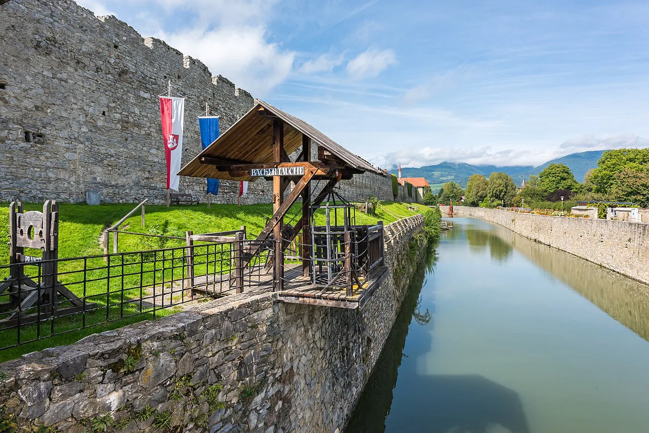 The water-filled moat beside Friesach's town wall at the Olsa gate bridge.