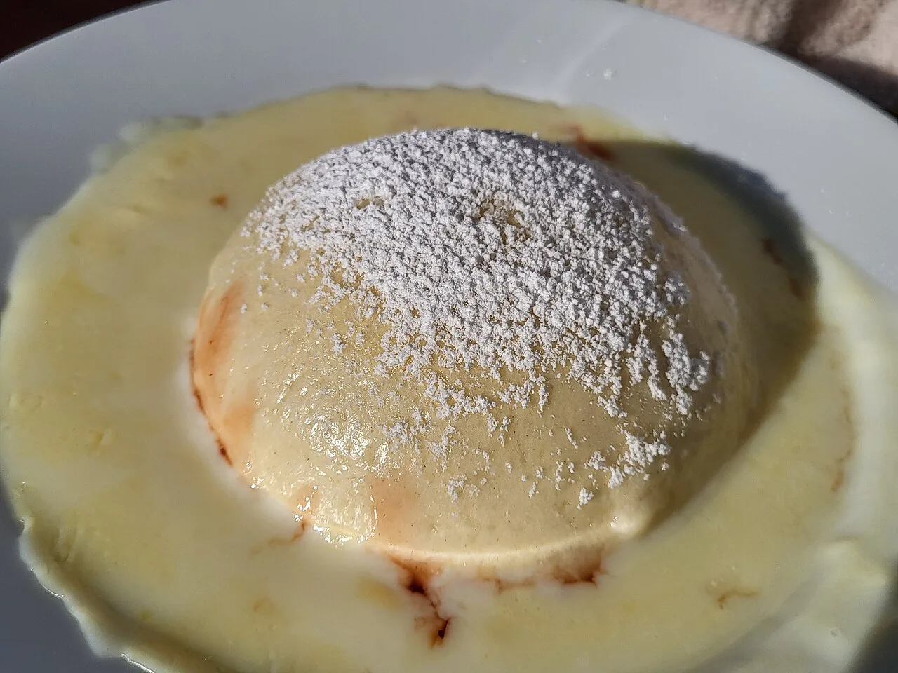 Germknödel with icing sugar served in vanilla sauce.