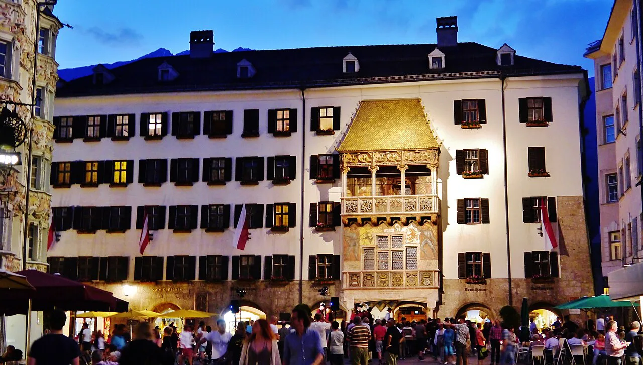 Innsbruck's Golden Roof lit up in the evening above a crowded square.