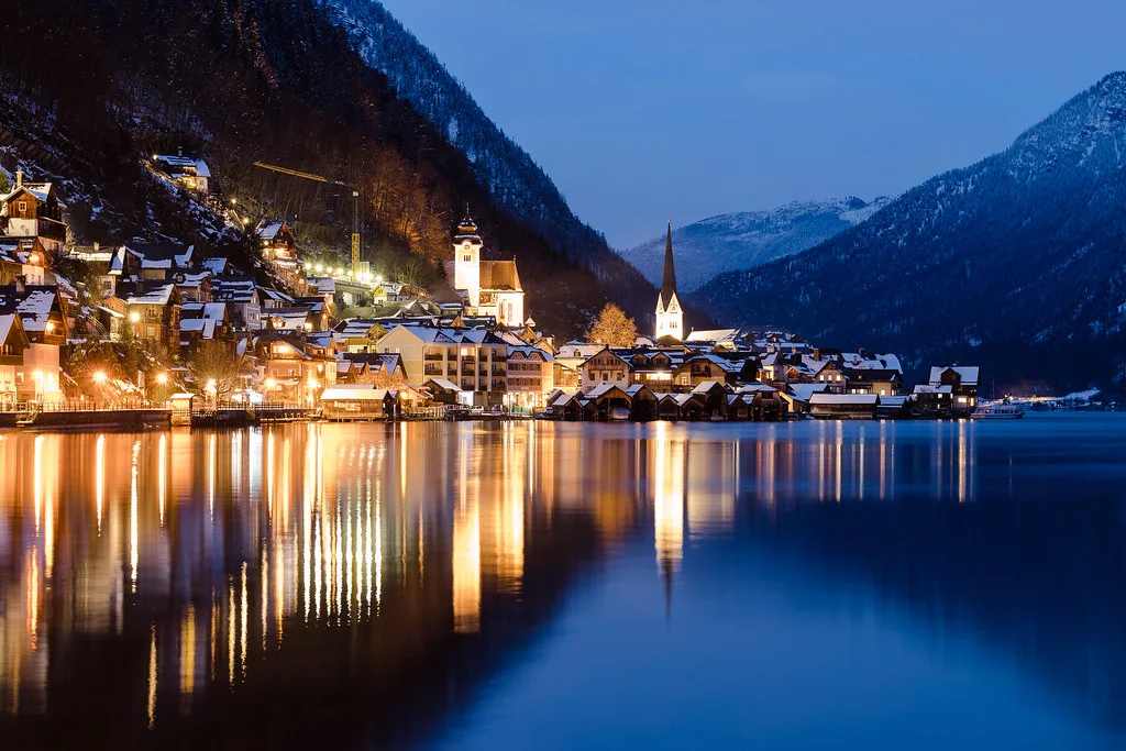 Hallstatt's lights reflected in the lake at dusk.
