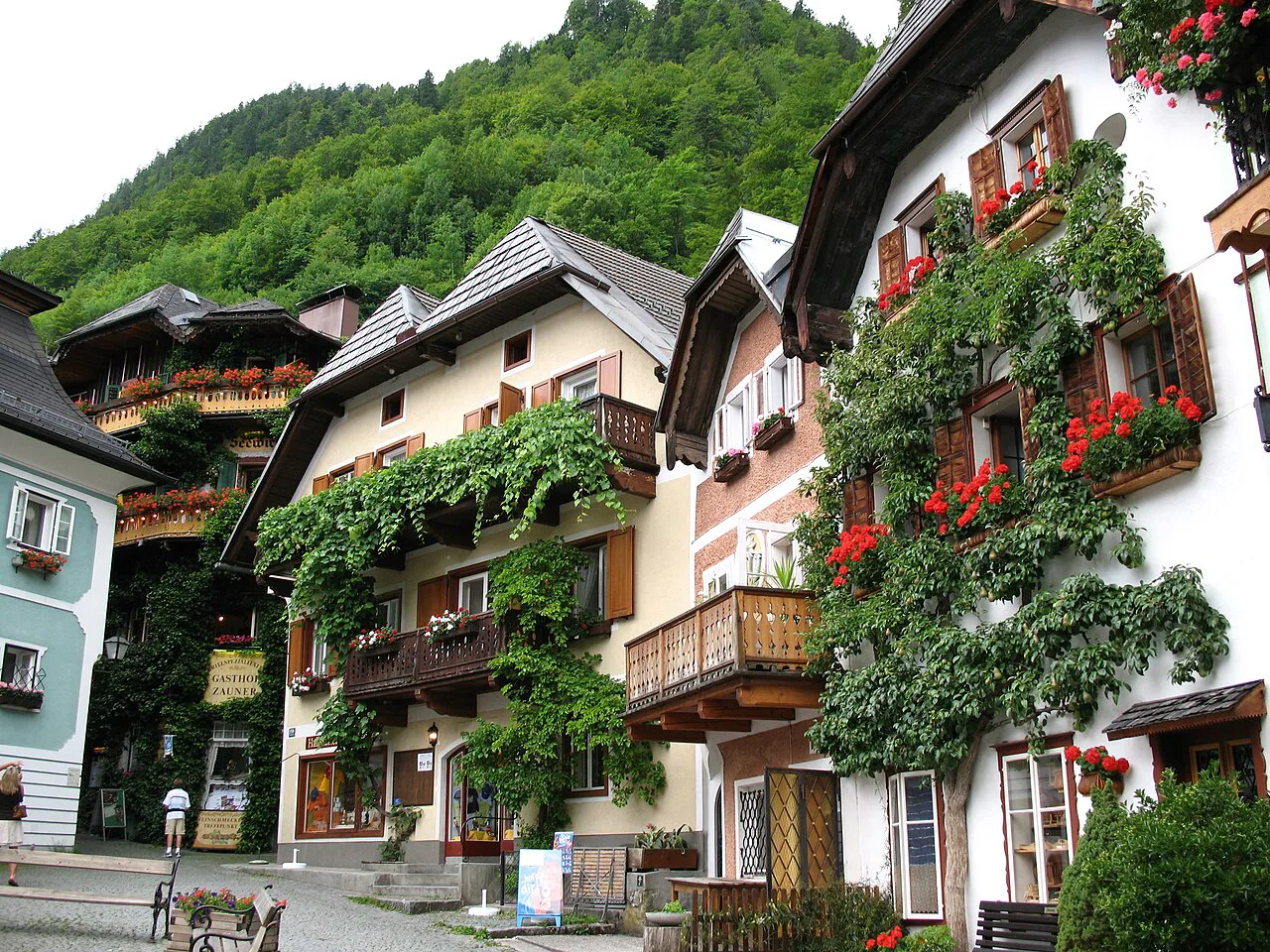 Flower-decked houses on the Marktplatz in Hallstatt, below the wooded mountainside.