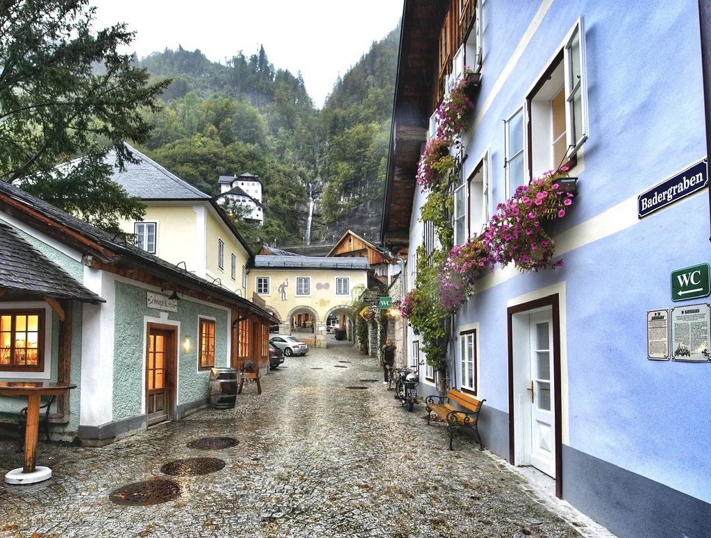A rain-wet lane lined with houses and flower boxes on Badergraben in Hallstatt.