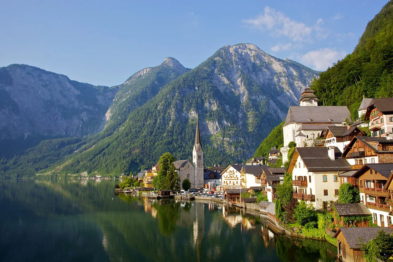 Hallstatt's lakeside houses and church spire reflected in the Hallstätter See below the mountains.