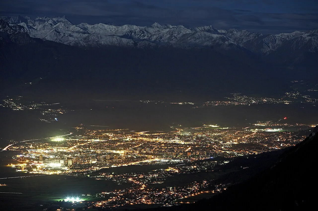 Innsbruck lit up at night in the Inn valley, with the Alps above.
