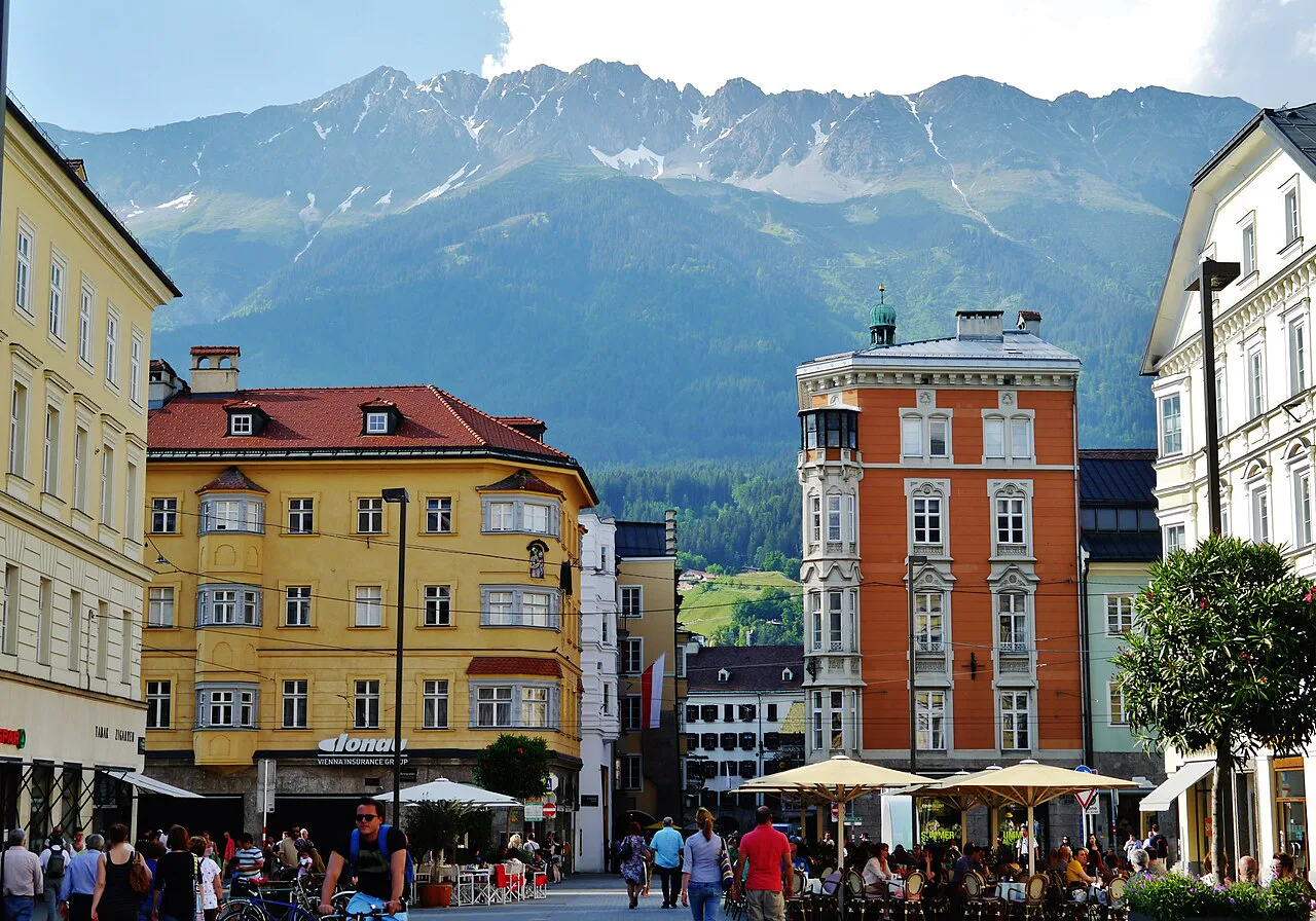 Colourful buildings in Innsbruck's old town with mountains rising behind.