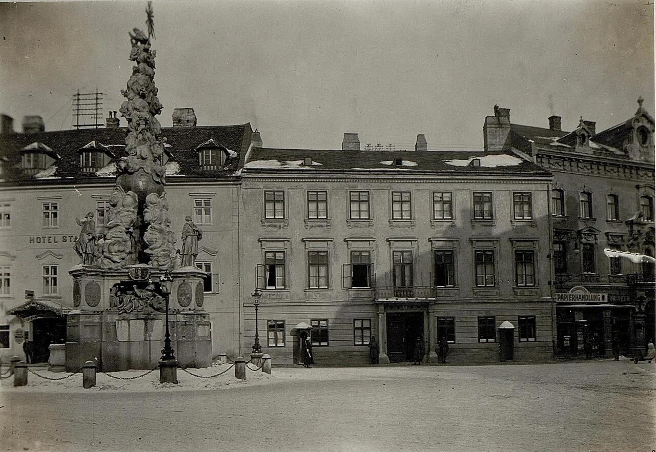 A historic photograph of the Kaiserhaus in Baden bei Wien beside the plague column.