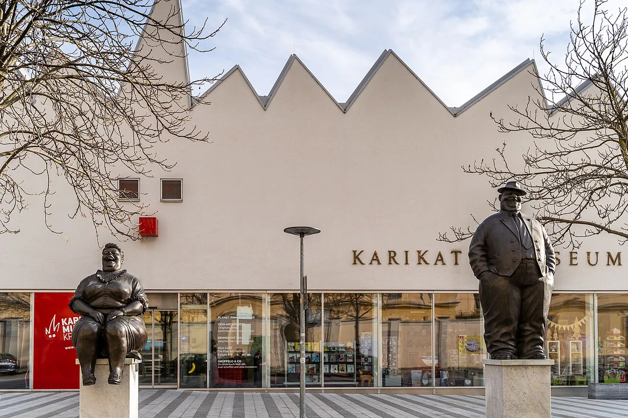 The entrance of the Karikaturmuseum Krems, with bronze figures outside.