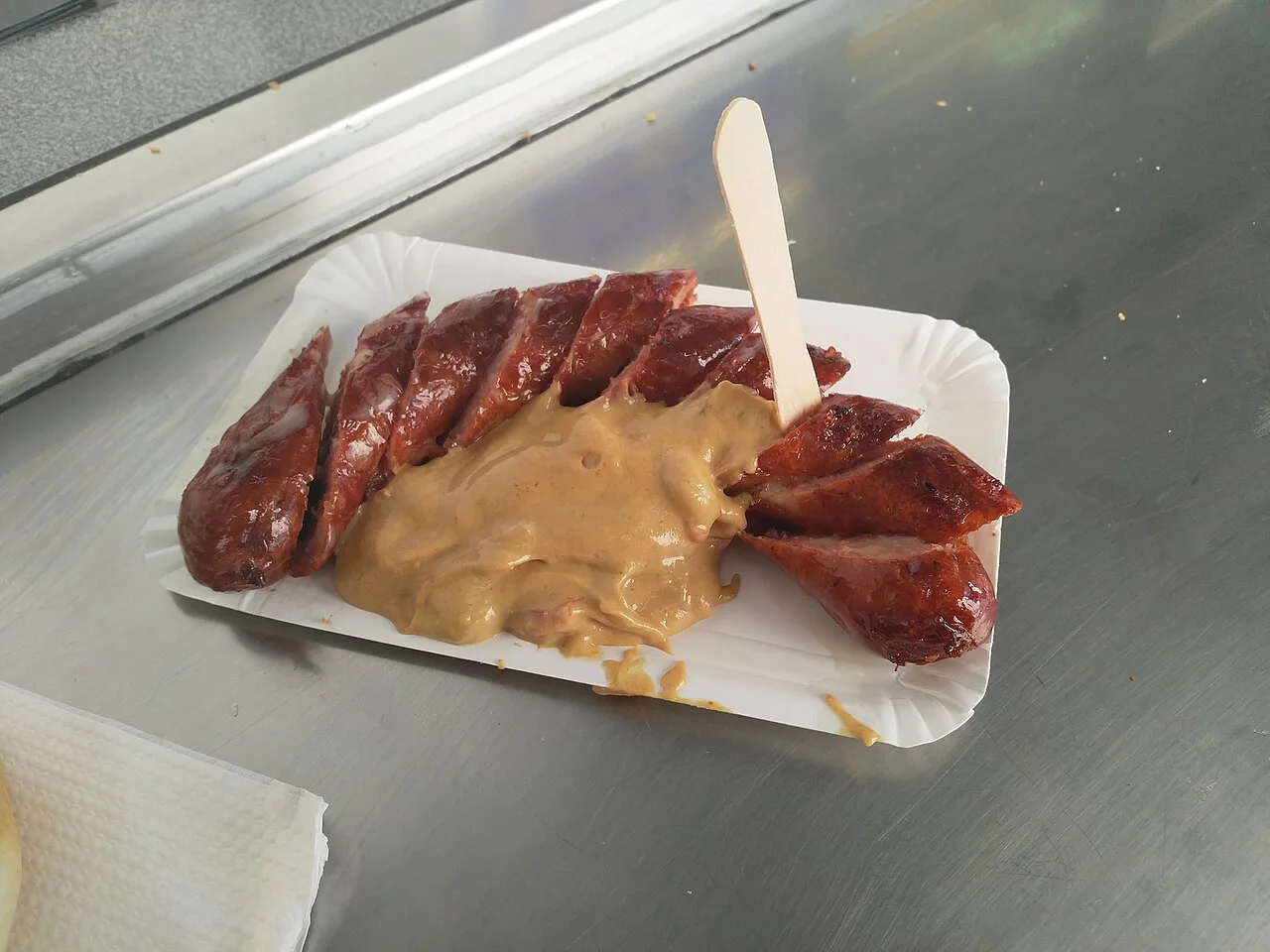 Sliced Käsekrainer sausage with mustard on a paper tray in Graz.
