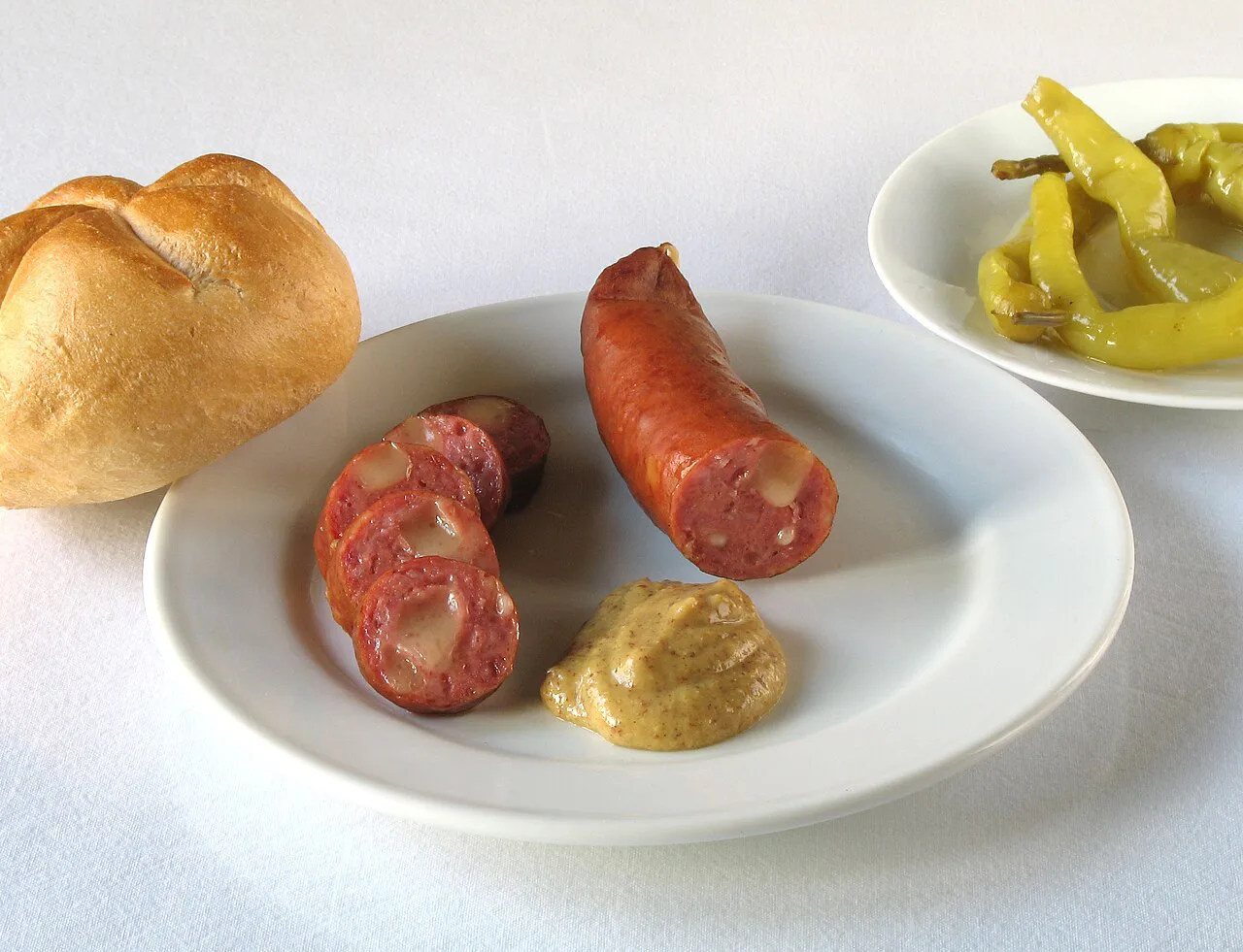 Käsekrainer with sweet Kremser mustard, a Semmel roll and pickled peppers.