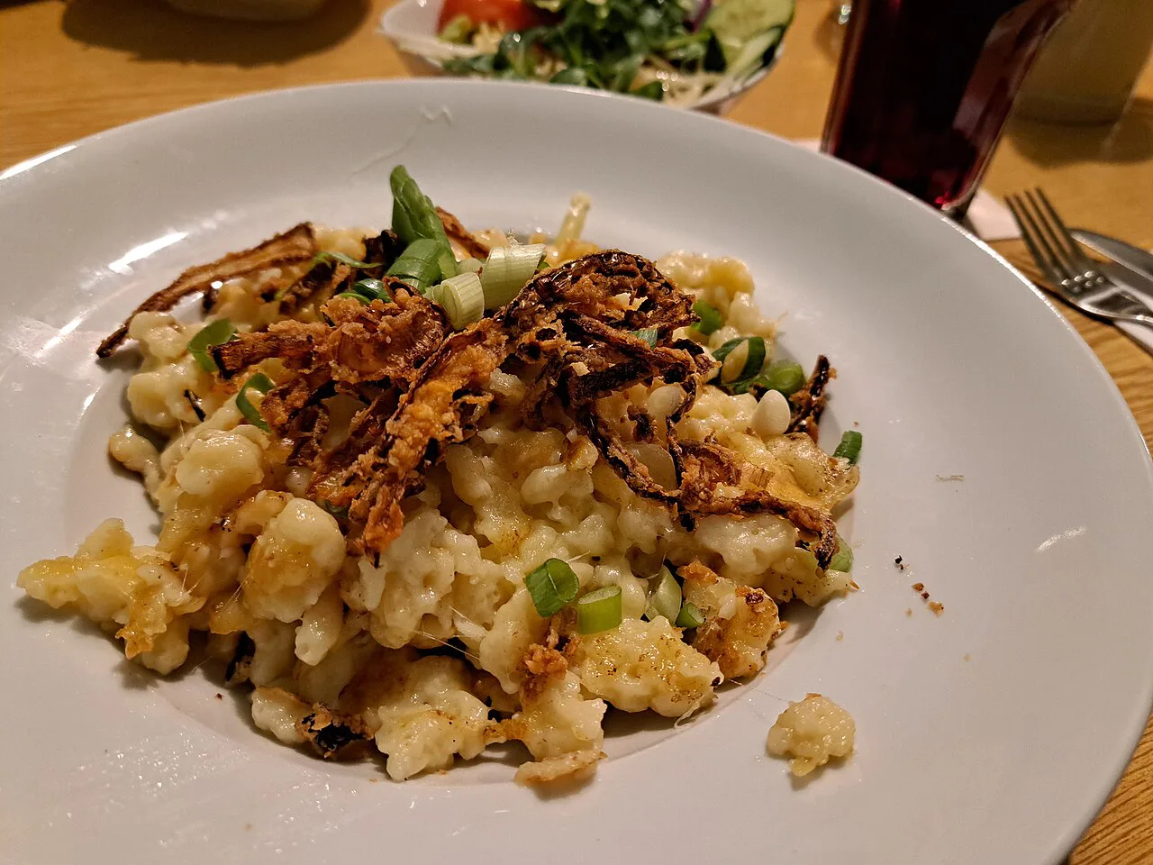A plate of Käsespätzle with crispy fried onions.