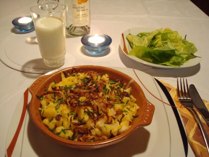 A dish of Kasnocken topped with crispy onions, served with a green salad.