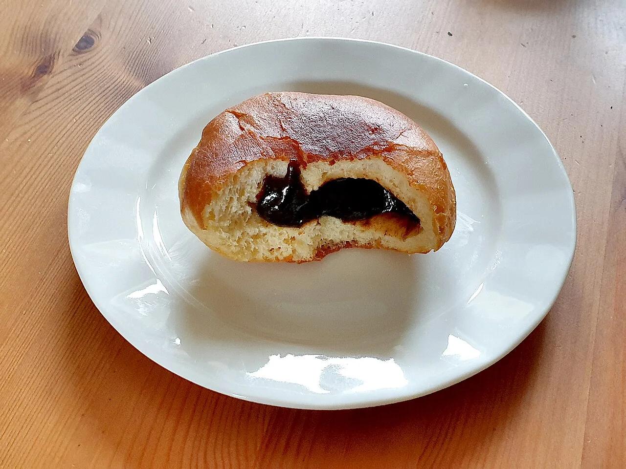 A homemade Krapfen doughnut bitten open to show its plum butter filling.