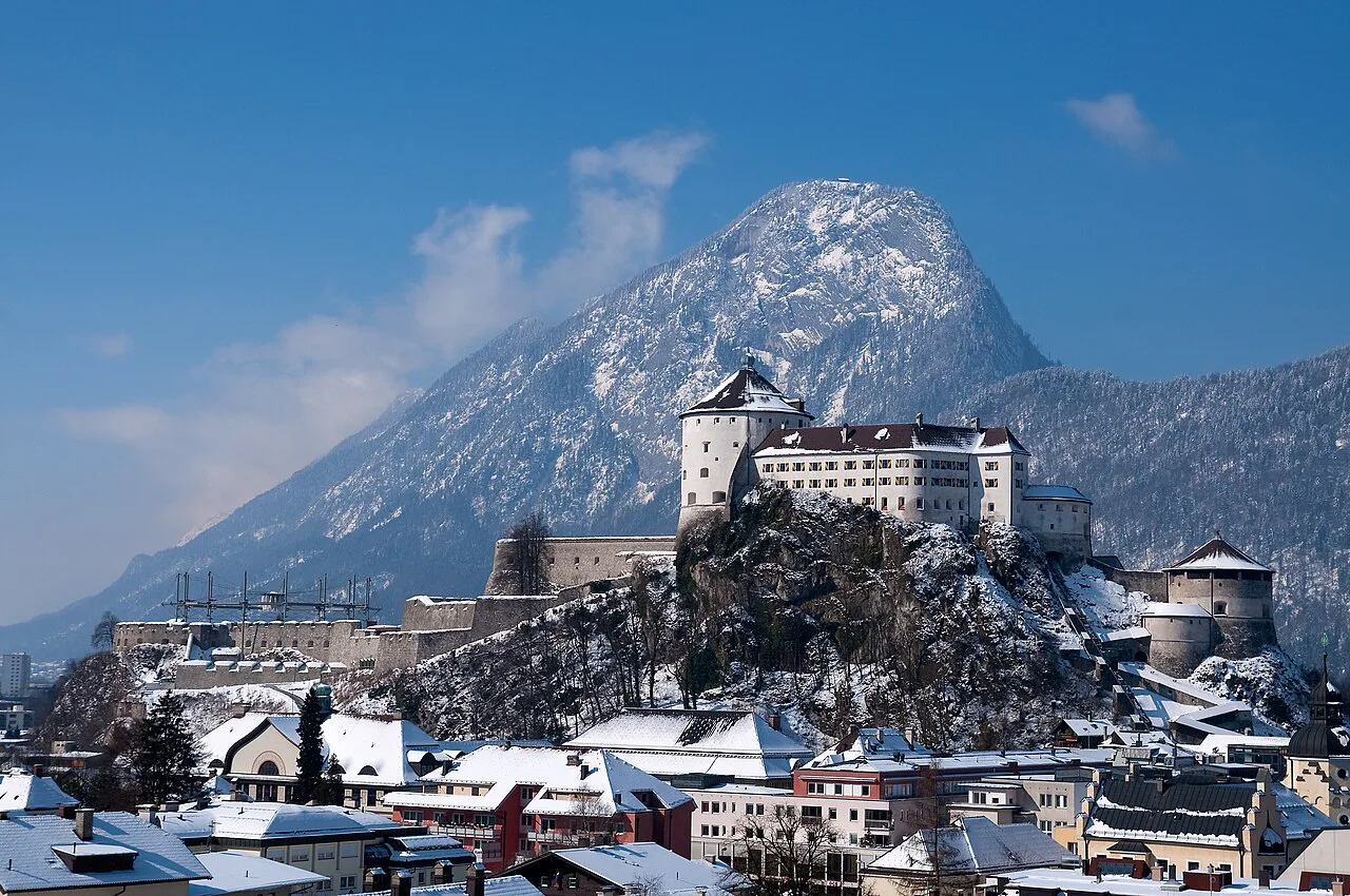 Kufstein Fortress above snow-covered Kufstein with a mountain behind.
