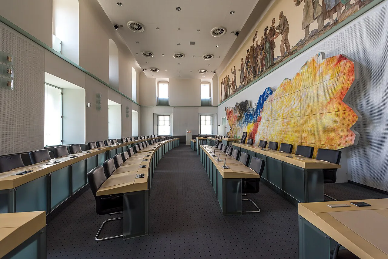 The council chamber inside Klagenfurt's Landhaus, with its large modern wall artwork.