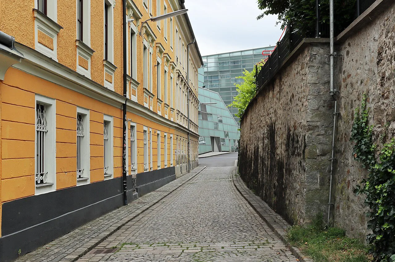 The cobbled Verlängerte Kirchengasse in Linz, with the glass Ars Electronica Center at its end.