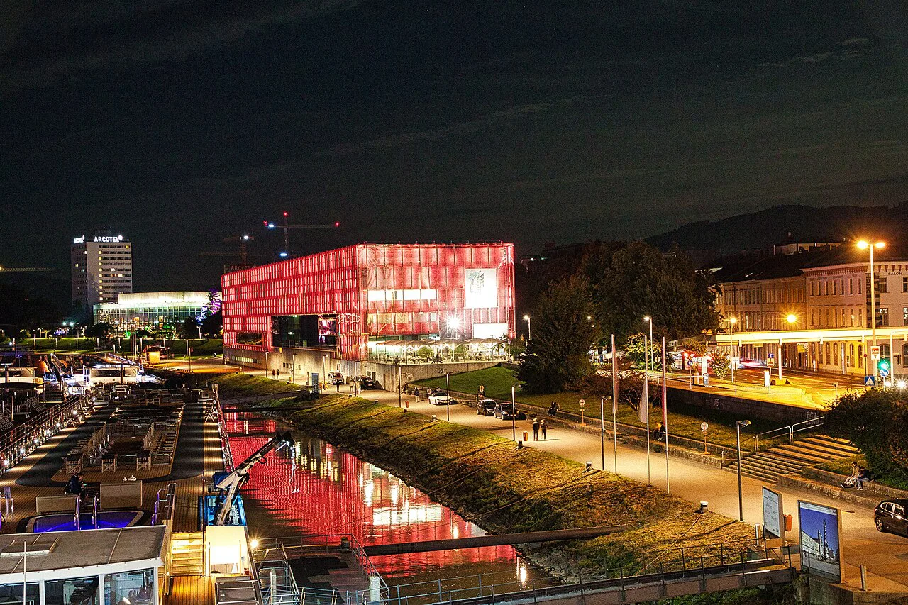 The Lentos Art Museum lit up at night beside the Danube in Linz.
