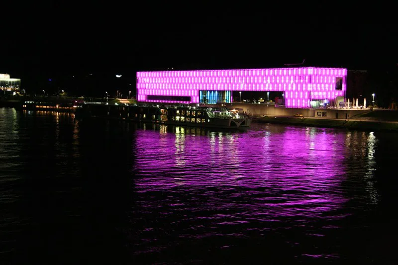 The Lentos Art Museum lit pink at night and reflected in the Danube, Linz.