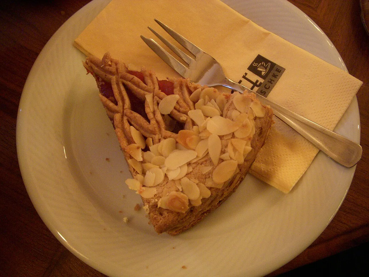 A slice of lattice-topped Linzer Torte with flaked almonds, served on a plate.
