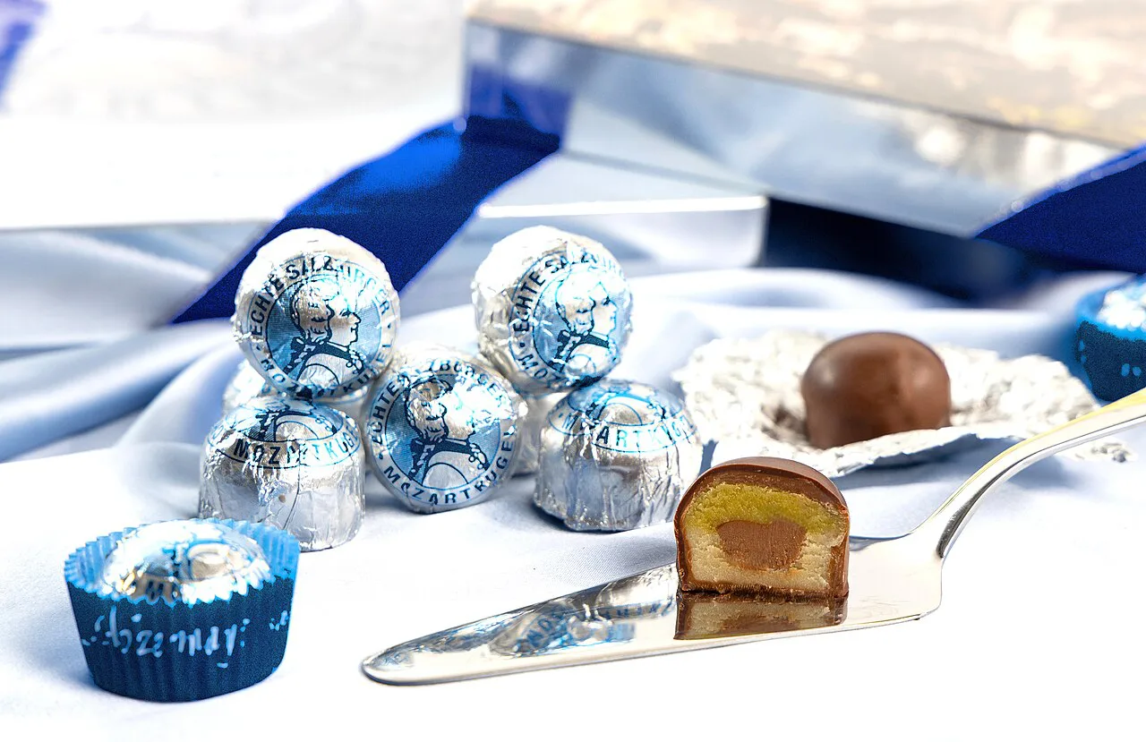 Foil-wrapped Salzburg Mozartkugeln, with one cut open to show the marzipan and nougat centre.