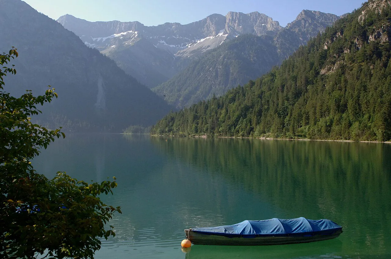 A boat on the green water of the Plansee below the mountains.