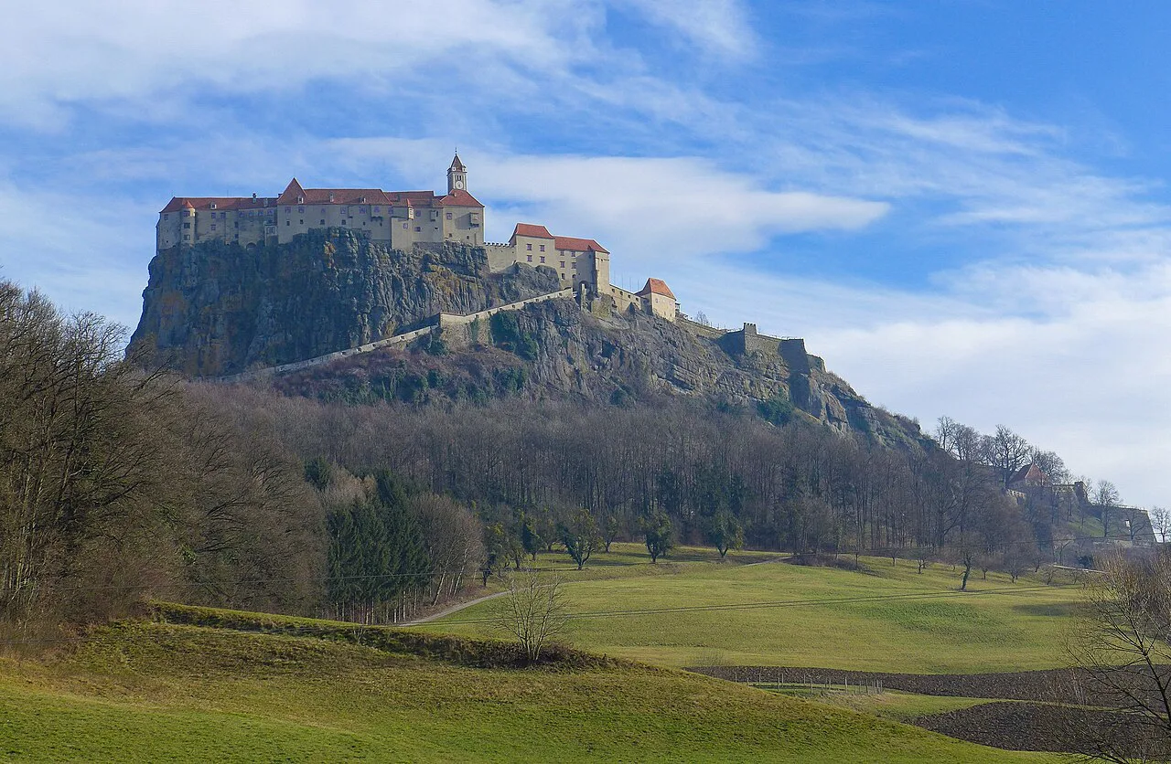 Riegersburg Castle crowning its rocky hill, seen across meadows from the south.