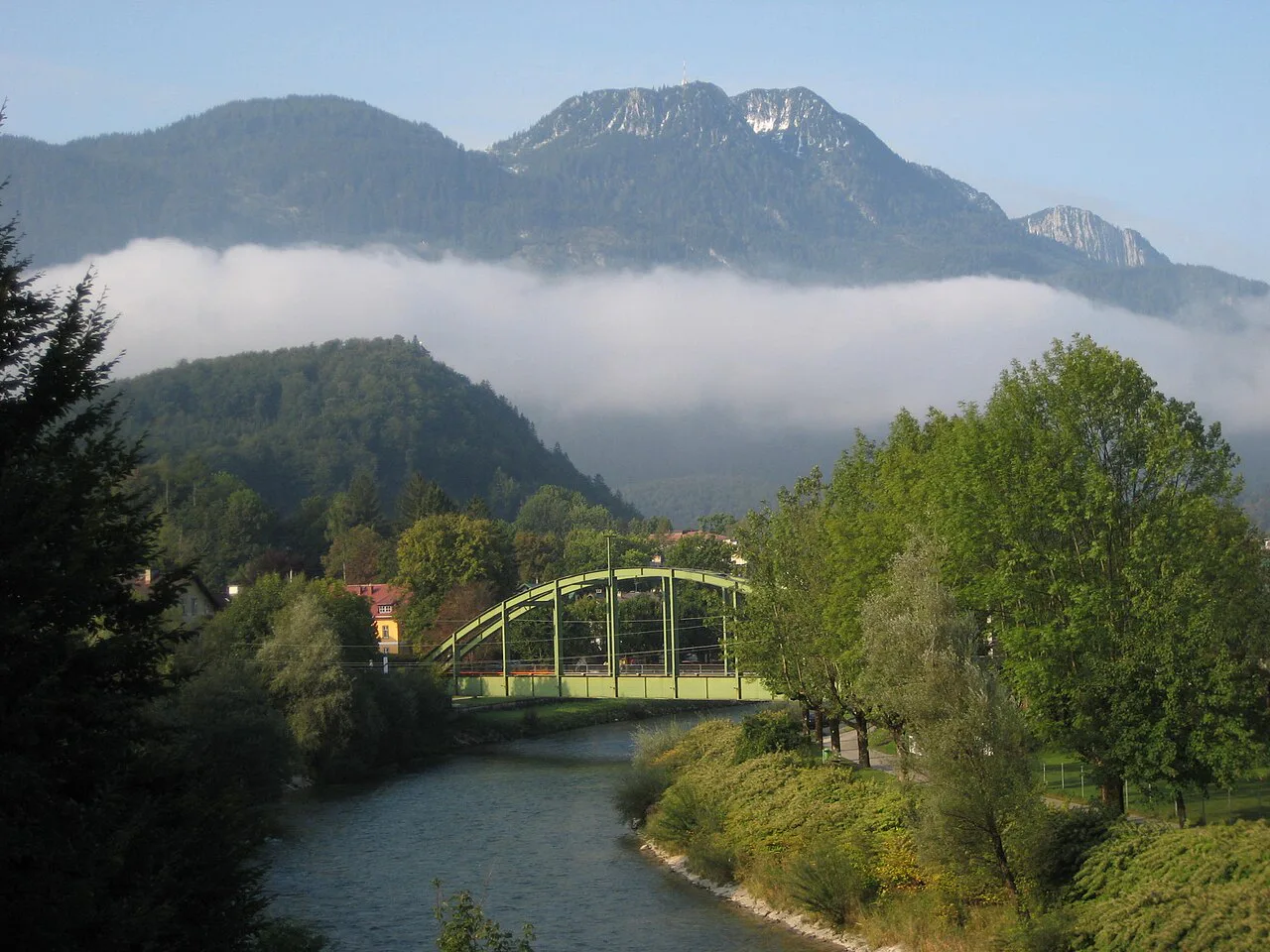 The wooded Siriuskogl under cloud above the Traun and its bridge in Bad Ischl.