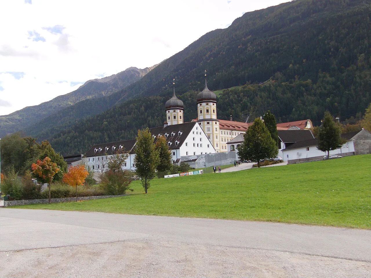 Stams Abbey in the Inn valley with forested mountains behind.
