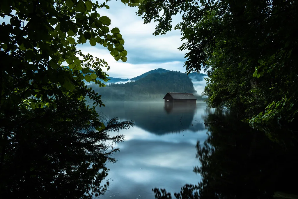A boathouse reflected in the calm water of the Almsee in Upper Austria.