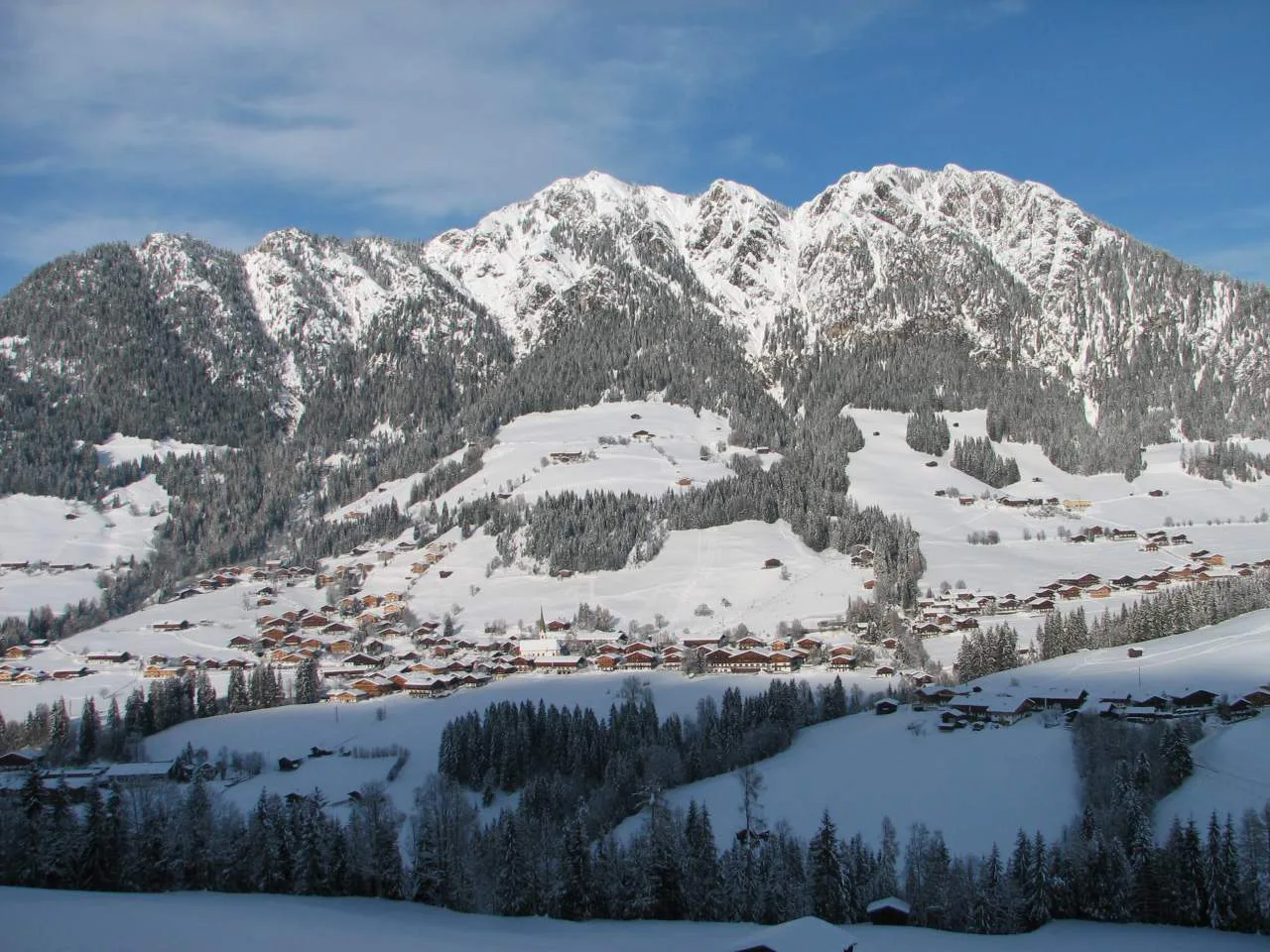 Alpbach in winter, with snow-covered mountains rising above the village.