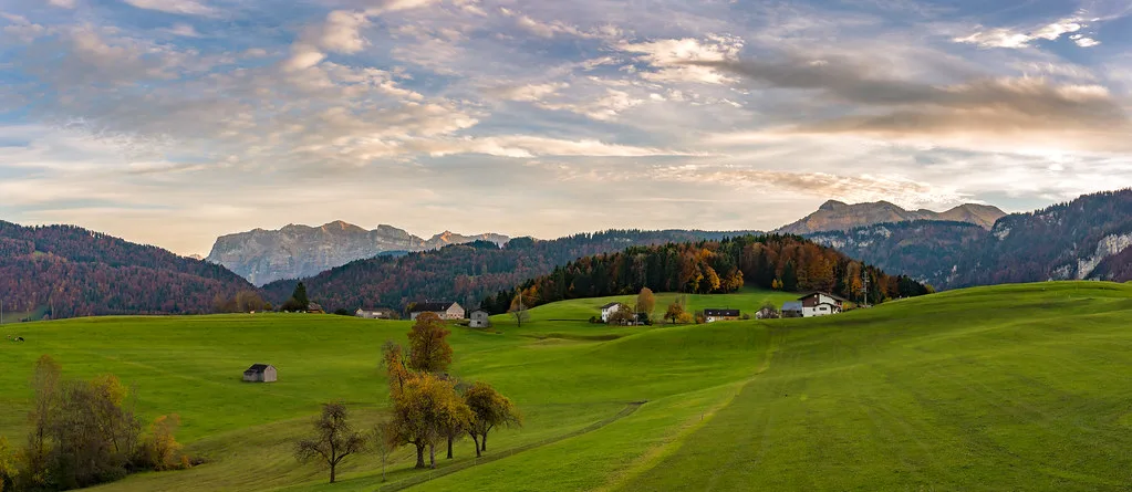 Autumn meadows above Schwarzenberg in the Bregenzerwald, Vorarlberg, with mountains behind.