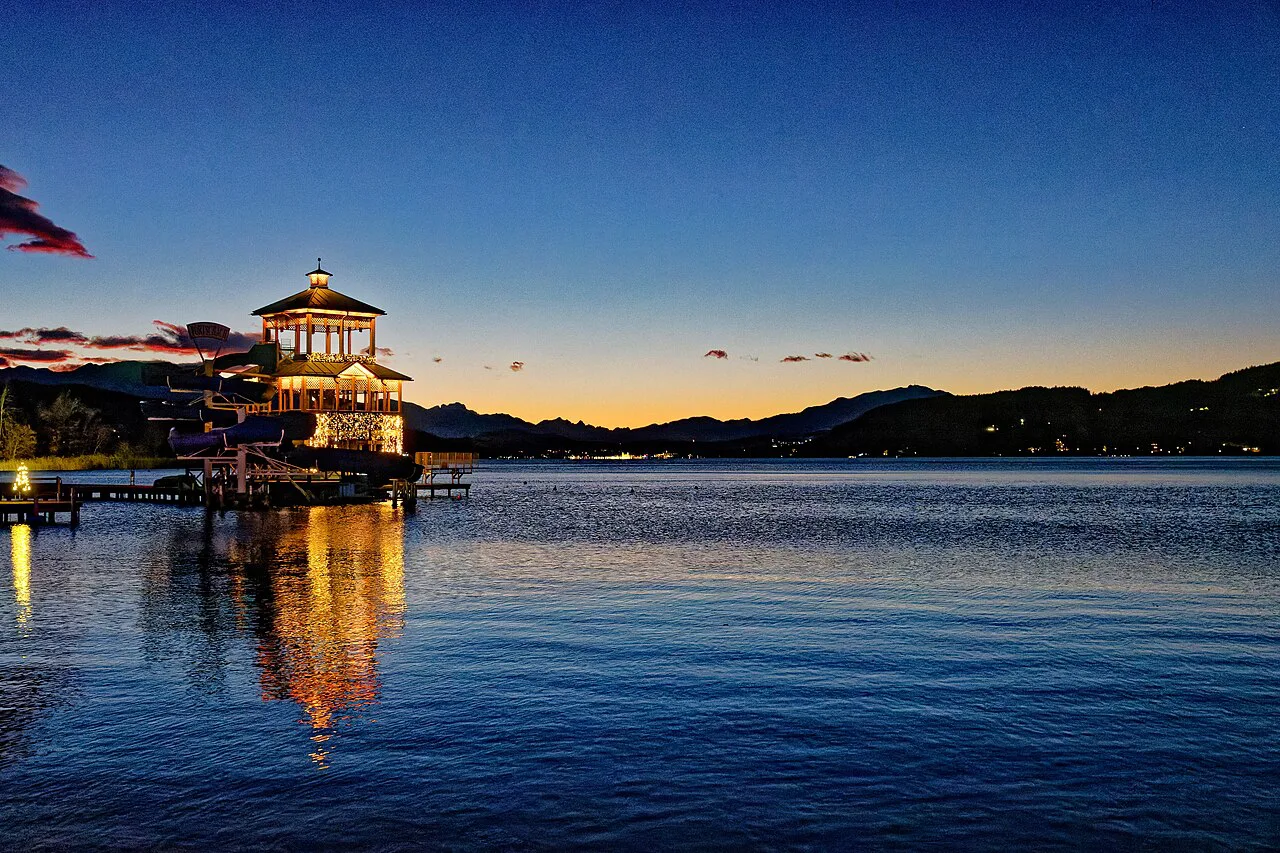 A lakeside pavilion lit up at dusk for Christmas on the Wörthersee.